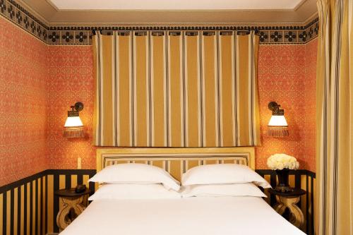 sypialnia z łóżkiem i ścianą w paski w obiekcie Hôtel Bourg Tibourg w Paryżu