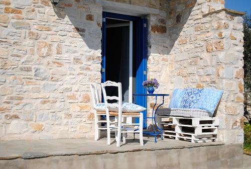 two chairs and a table on the porch of a stone building at Sunrise View Lefkes in Lefkes