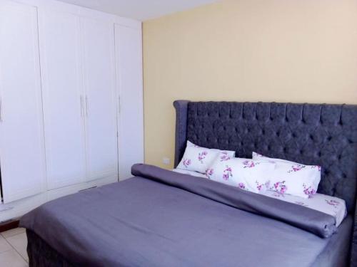 a bed with a blue headboard and two pillows at Greenvale's 2 Bedroom in Eldoret