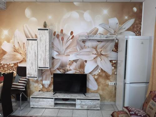 un salon avec une télévision et une fresque murale florale dans l'établissement Eden Studio, à Constanţa