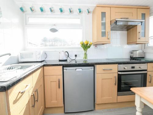 a kitchen with wooden cabinets and a dishwasher at Wagtails in Dartmouth