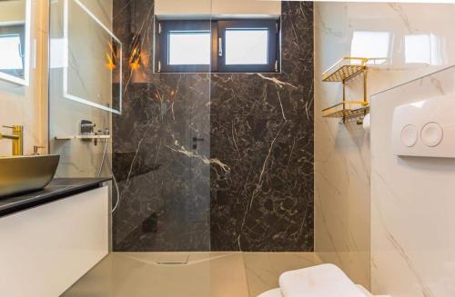 uma casa de banho com uma cabina de duche em vidro e um lavatório. em ŽIŽI exclusive apartments em Tučepi