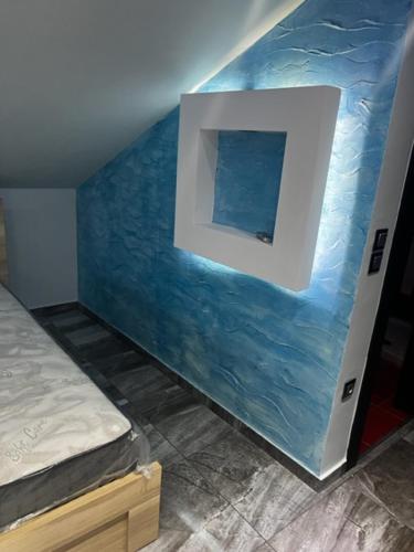 a bedroom with a blue wall with a window at MESAGGALA PALACE No 3 FIRSTLINE SEA in Néa Meságkala