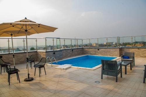 a swimming pool on a roof with chairs and an umbrella at Geneva Hotel in Douala