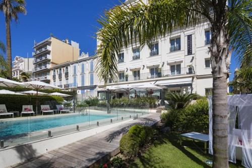 um grande edifício com uma piscina em frente a um edifício em Hôtel Le Canberra em Cannes