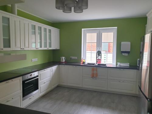 a kitchen with white cabinets and green walls at Tamme Teemaja in Iisaku