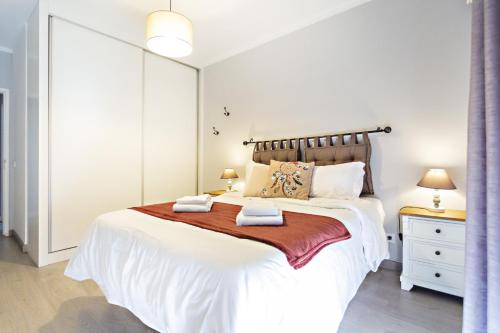 um quarto com uma grande cama branca com duas toalhas em Apartamento Gulbenkian em Faro