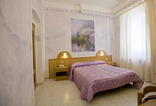 a bedroom with a purple bed and a painting on the wall at Albergo Ristorante Turchino in Campo Ligure