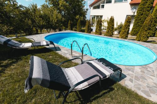 a swimming pool with two lounge chairs in front of a house at Vila Bucium Club in Iaşi