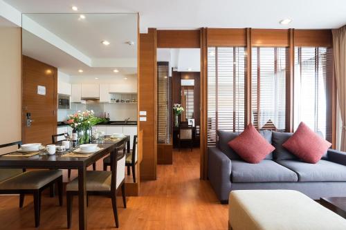 a living room and dining room with a couch and a table at Amanta Hotel & Residence Ratchada in Bangkok