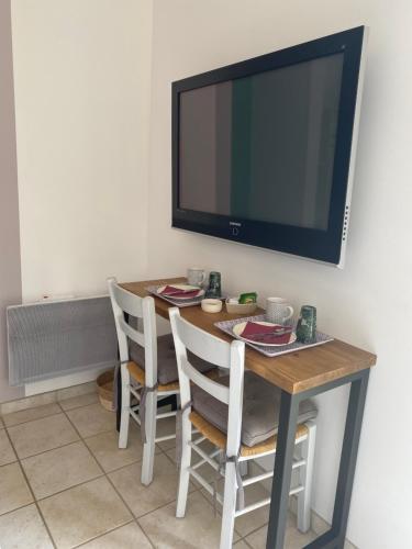 uma mesa de jantar com cadeiras e uma televisão de ecrã plano em Chambre d'hôtes Les Boutons d'Or em Saint-Chamas
