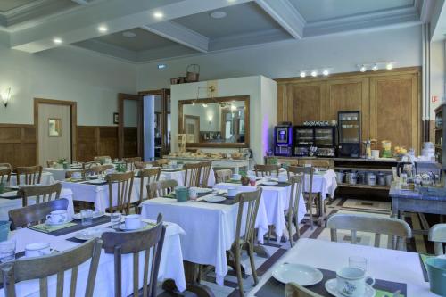 ル・ブール・ドアザンにあるSport'Hotel-Aparthotel de Milanの白いテーブルと椅子のあるダイニングルーム