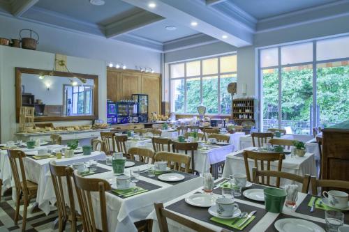 a restaurant with white tables and chairs and windows at Sport'Hotel-Aparthotel de Milan in Le Bourg-dʼOisans