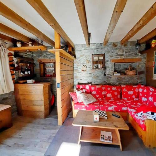 a living room with a red couch and a table at Baita Il Focolare - Your Mountain Holiday in Premana