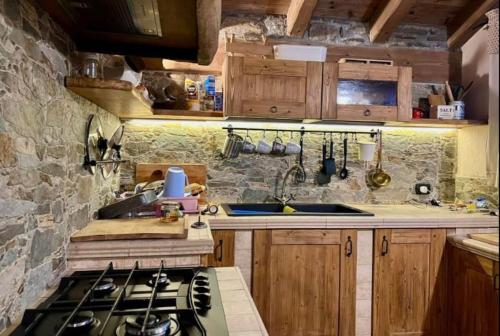 a kitchen with a stove and a stone wall at Baita Il Focolare - Your Mountain Holiday in Premana