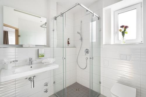 a white bathroom with a shower and a sink at Hotel Drei Rosen in Moosburg