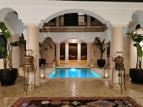 uma piscina num quarto grande com colunas e plantas em Riad Bijoux em Marraquexe