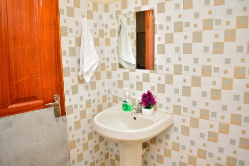 a bathroom with a white sink and a mirror at Rozie Apartment in Kisumu