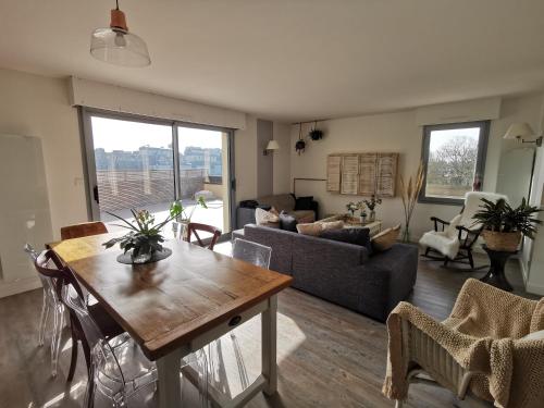ein Wohnzimmer mit einem Tisch und einem Sofa in der Unterkunft Au numéro Cinq in Donville-les-Bains