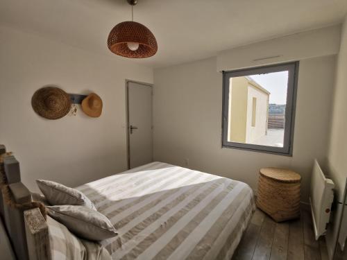 een slaapkamer met een bed en een raam bij Au numéro Cinq in Donville-les-Bains