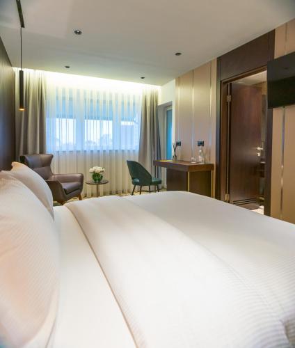 a bedroom with a large white bed and a living room at Emery Hotel in Pristina