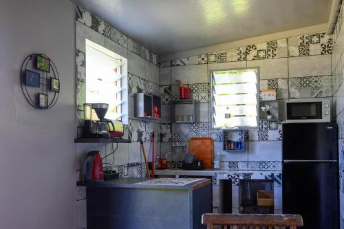 a kitchen with a black refrigerator and a counter at Les bungalows meublés du Pharest in Sainte-Suzanne