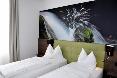 2 camas en una habitación de hotel con un mural de cascada en Brauhaus Falkenstein, en Lienz