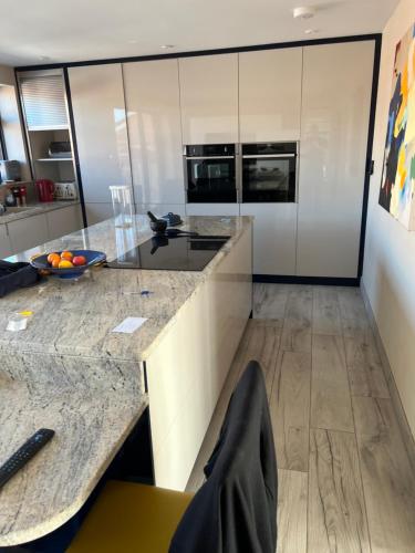 a kitchen with marble counter tops and white cabinets at Sea breeze Exmouth in Lympstone