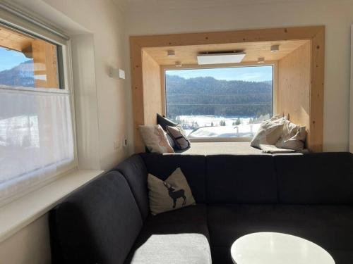 a living room with a black couch and a window at Das Fenster zum See-Weissensee in Weissensee