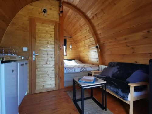 Habitación con sofá y cama en una cabaña de madera. en Ma cabane au fond du jardin en Porto Vecchio