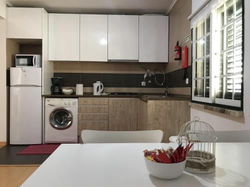 a kitchen with white cabinets and a table with a dishwasher at Oriente DNA Studios IV in Lisbon