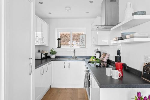 a white kitchen with white cabinets and a sink at Osprey 3, The Cove - Sea view - On site pool in Brixham