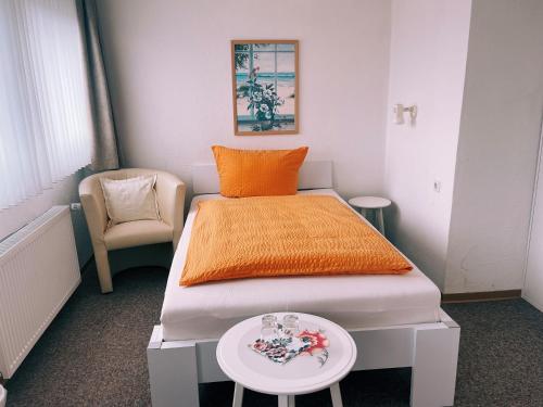 een slaapkamer met een bed met een oranje deken en een tafel bij Gästehaus Kehne in Horn-Bad Meinberg