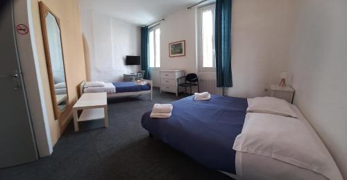 um quarto de hotel com duas camas e um espelho em Hôtel Du Cours em Pertuis