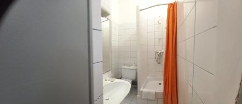 uma casa de banho com uma cortina de chuveiro laranja e um WC. em Hôtel Du Cours em Pertuis