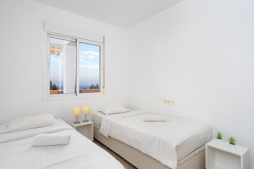 2 łóżka w białym pokoju z oknem w obiekcie Cozy penthouse in Torremolinos by Costarentals - Ref 09 w mieście Torremolinos