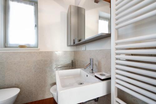 a white bathroom with a sink and a mirror at Casa Grazia - Appartamento Luce in Gargnano