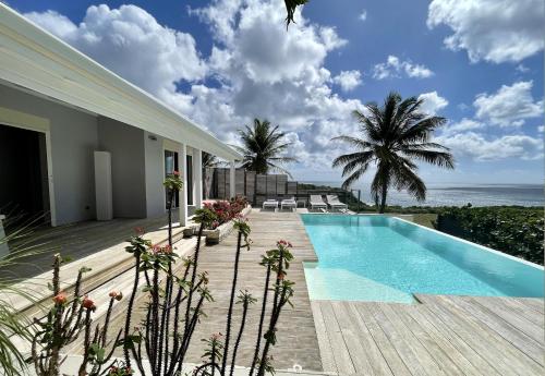 una casa con piscina y el océano en Villa Estheria, en Sainte-Anne
