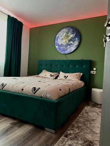 a green bedroom with a large bed with a globe on the wall at Apartamente A&A in Tîrgu Ocna