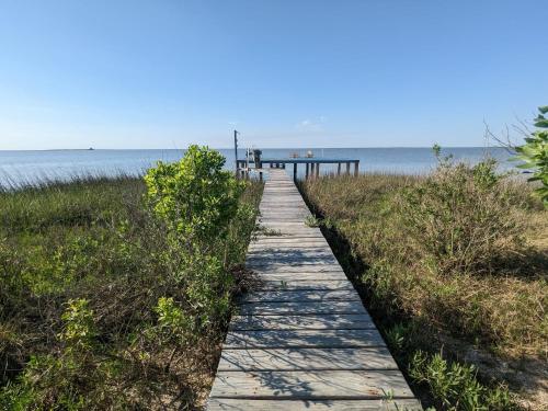 un paseo marítimo que conduce a un muelle en la playa en Glamping on the Bay with fishing dock en Bolivar Peninsula