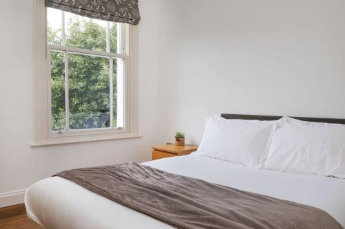 a bedroom with a white bed and a window at Comfy 1 bed flat in Tufnell Park in London
