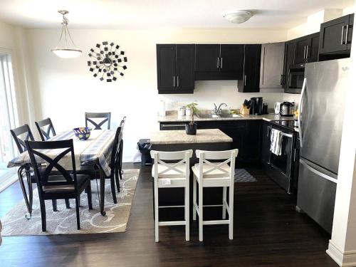 a kitchen with black cabinets and a table with chairs at Niagara sleeps 6 Cozy 3bed3bath Near Falls in Thorold