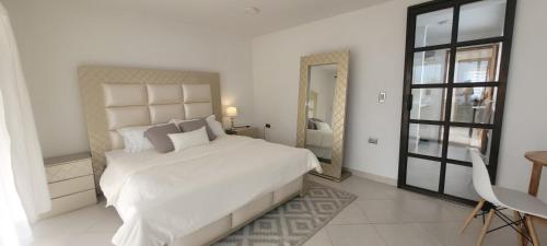 a white bedroom with a large bed and a window at Casa Suite Palmar del viento FRENTE, FRENTE AL MAR by Amauna in Moñitos
