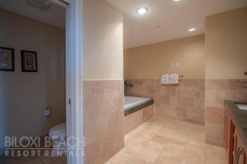 een badkamer met een bad, een toilet en een wastafel bij Ocean Club 701 in Biloxi