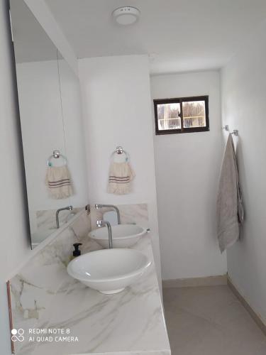 a white bathroom with two sinks and a mirror at Casa Suite Palmar del viento FRENTE, FRENTE AL MAR by Amauna in Moñitos