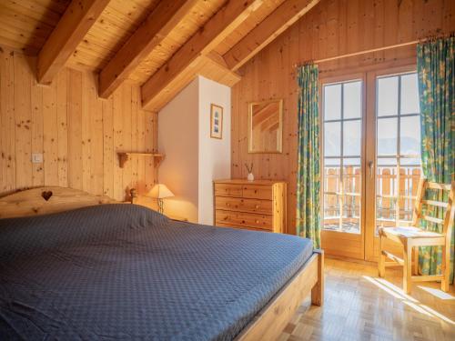 1 dormitorio con cama y ventana grande en Chalet Six des Armailles by Interhome, en Ovronnaz