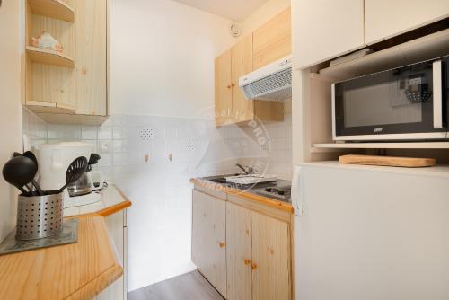 une petite cuisine avec un micro-ondes et un réfrigérateur dans l'établissement AS23038 - Studio cabine vue sur Parc avec box, au Grau-du-Roi