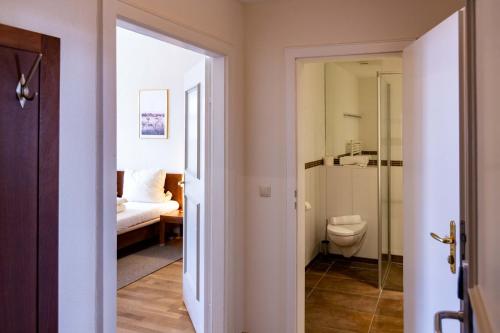 ein Bad mit einem WC und ein Schlafzimmer mit einem Bett in der Unterkunft Hotel Schyrenhof in Scheyern
