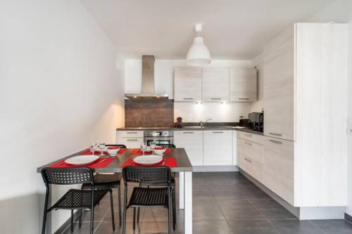 une cuisine avec des armoires blanches et une table avec des chaises dans l'établissement Le Rive Gauche, à Saint-Jorioz