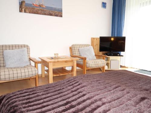 um quarto com uma cama e duas cadeiras e uma televisão em Apartment Rosengrund by Interhome em Büsum